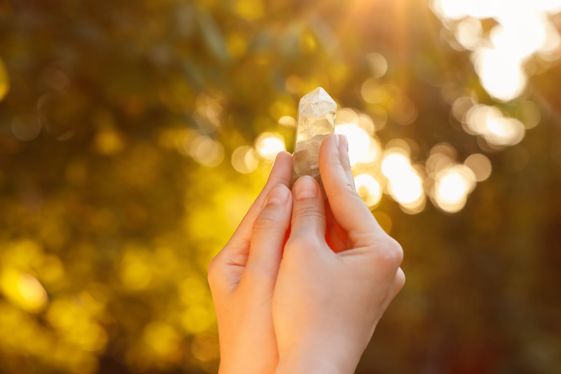 Woman meditating with crystal to heal or restore her aura outdoors, closeup