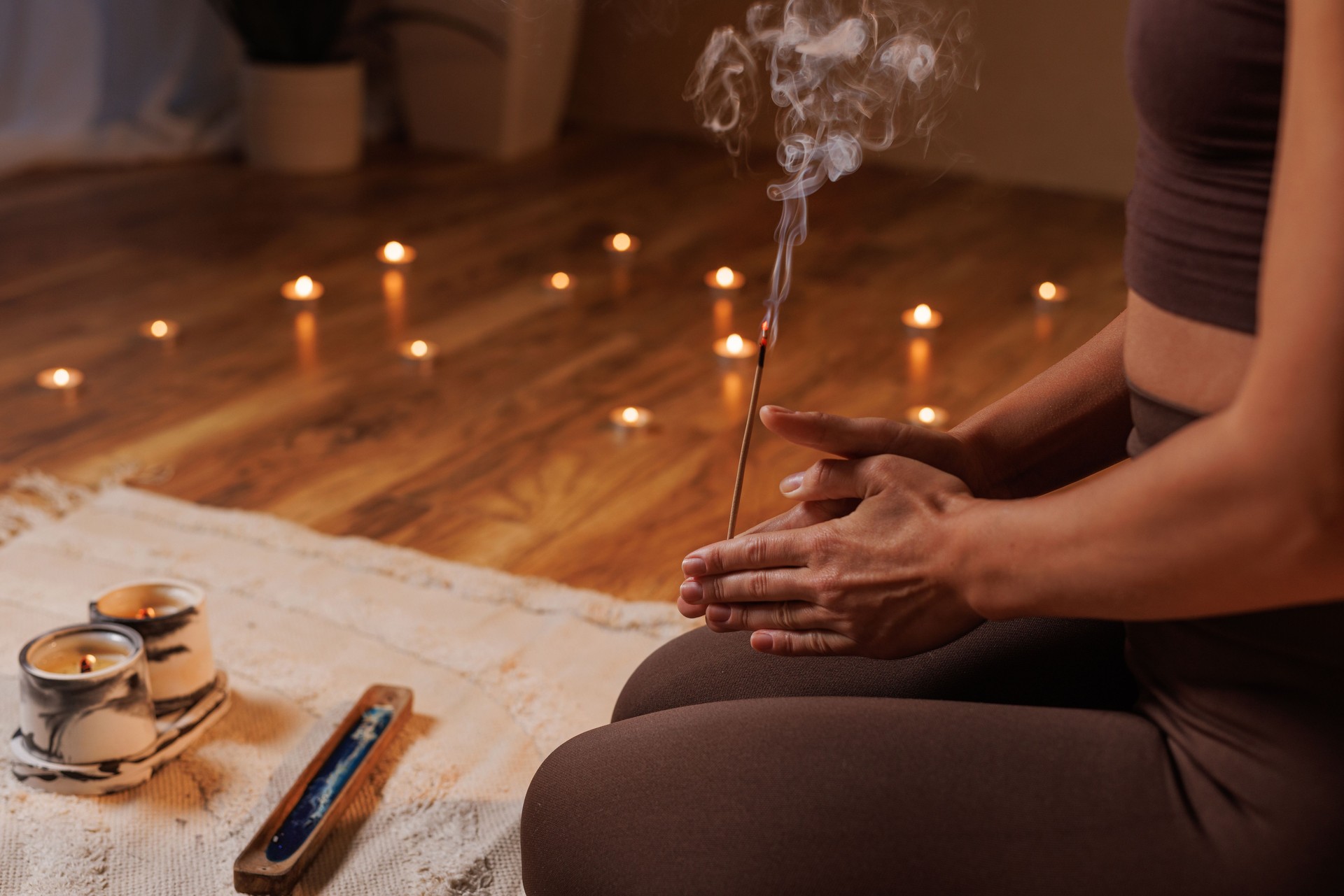 Close-up of a woman meditating with burning incense and candles, creating a calm and peaceful atmosphere.